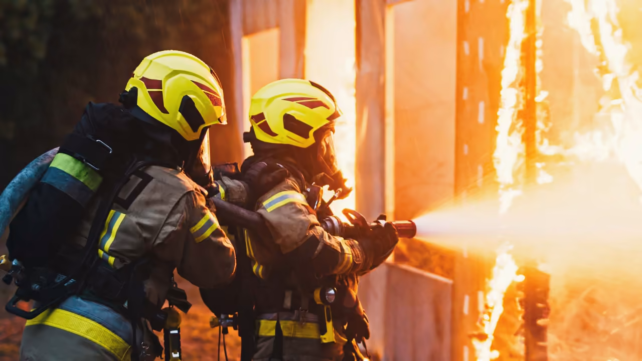 Feuerwehrleute in Schutzkleidung löschen einen Brand