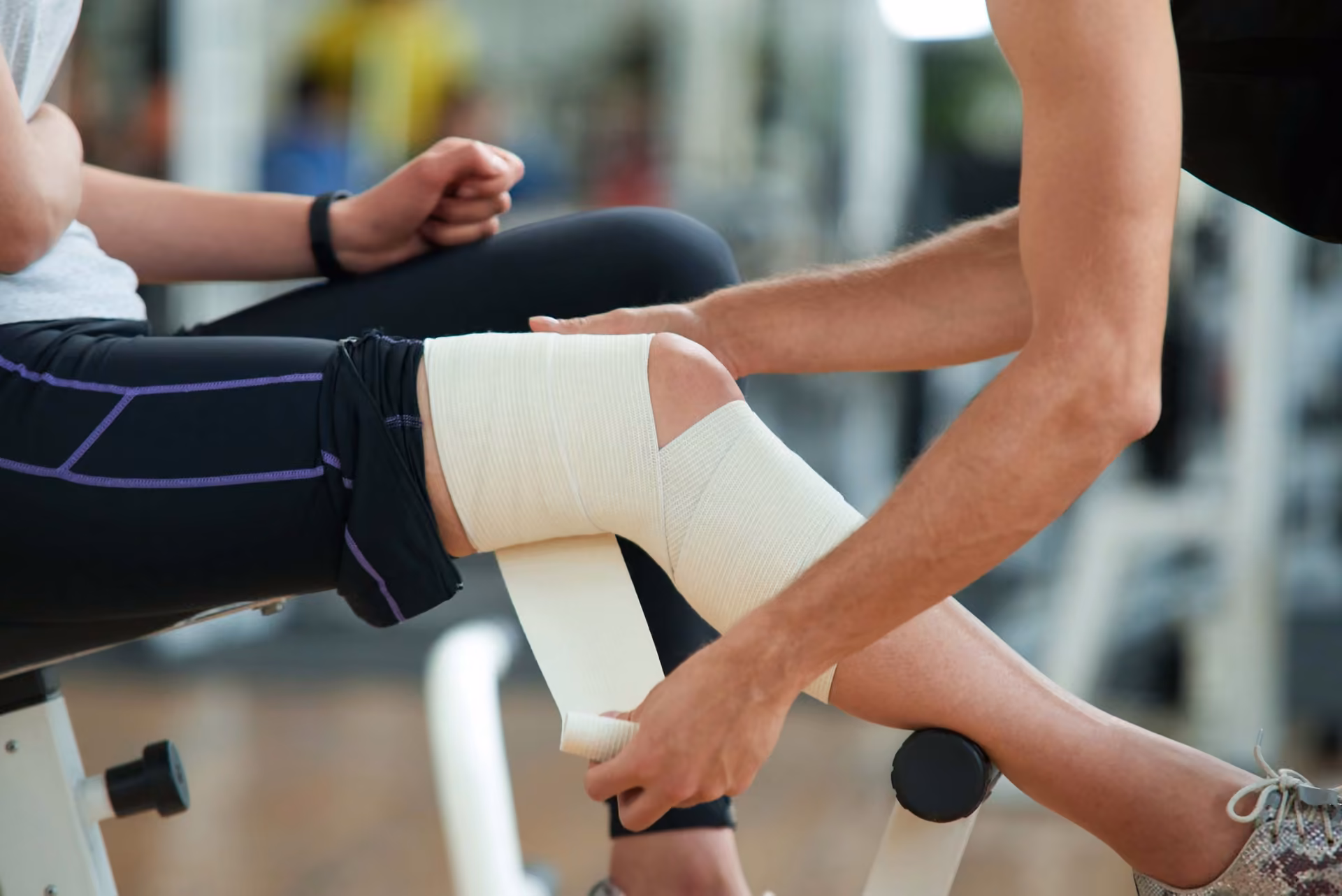Physiotherapeut legt eine Kniebandage an