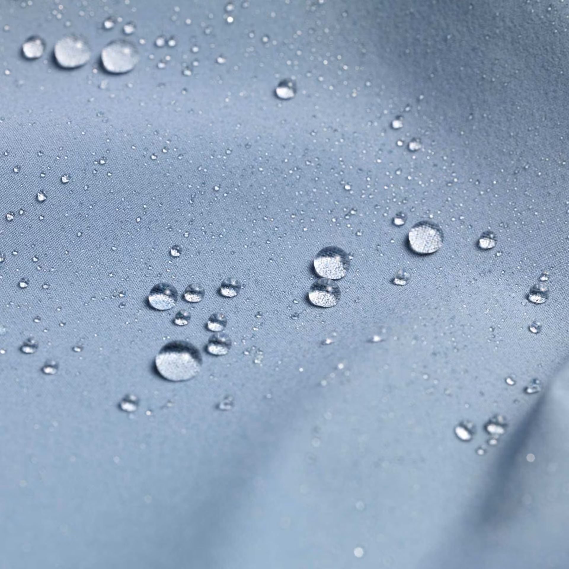 Wassertropfen perlen auf einem grauen Gewebe ab